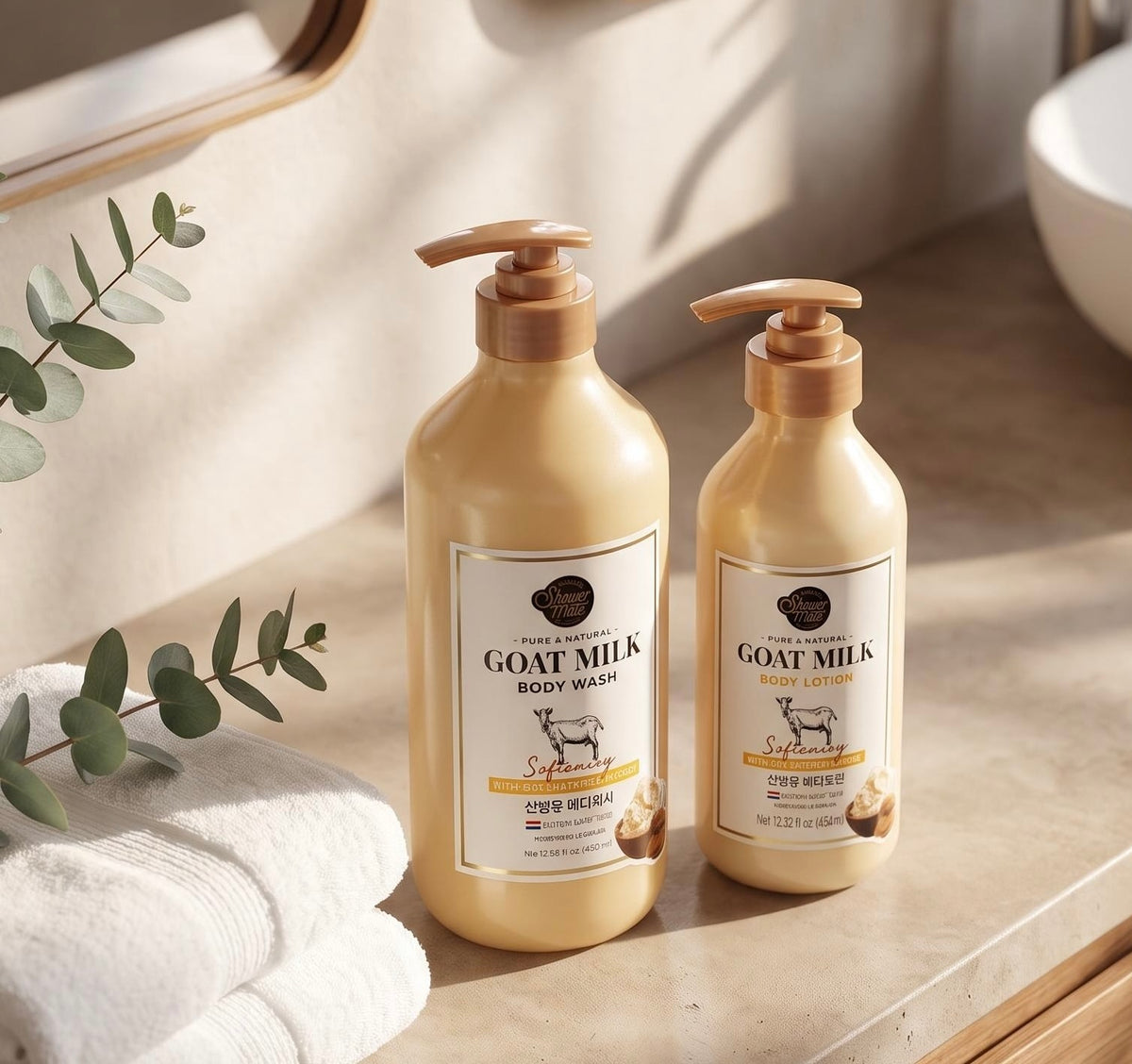 Two pump bottles of Soft Science Goat Milk Body Care products, including body wash and body lotion, displayed on a beige stone countertop with white towels, a mirror, and eucalyptus leaves in a warm, sunlit bathroom setting.