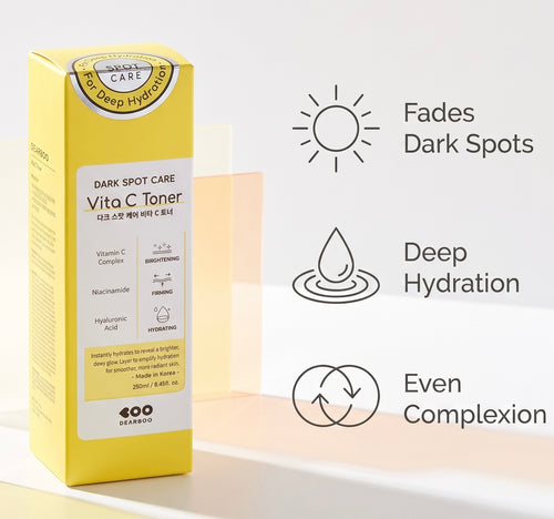 A yellow box of Soo Beruby Vita C Toner Dark Spot Care stands on a white surface against a light beige background. To the right are three black line icons with text: a sun reading 'Fades Dark Spots,' a water droplet reading 'Deep Hydration,' and a circular arrow reading 'Even Complexion.