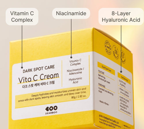 A yellow and white box of DEARBOO Vita C Cream Dark Spot Care shown on a soft beige background, with three callout labels pointing to Vitamin C Complex, Niacinamide, and 8-Layer Hyaluronic Acid ingredients.